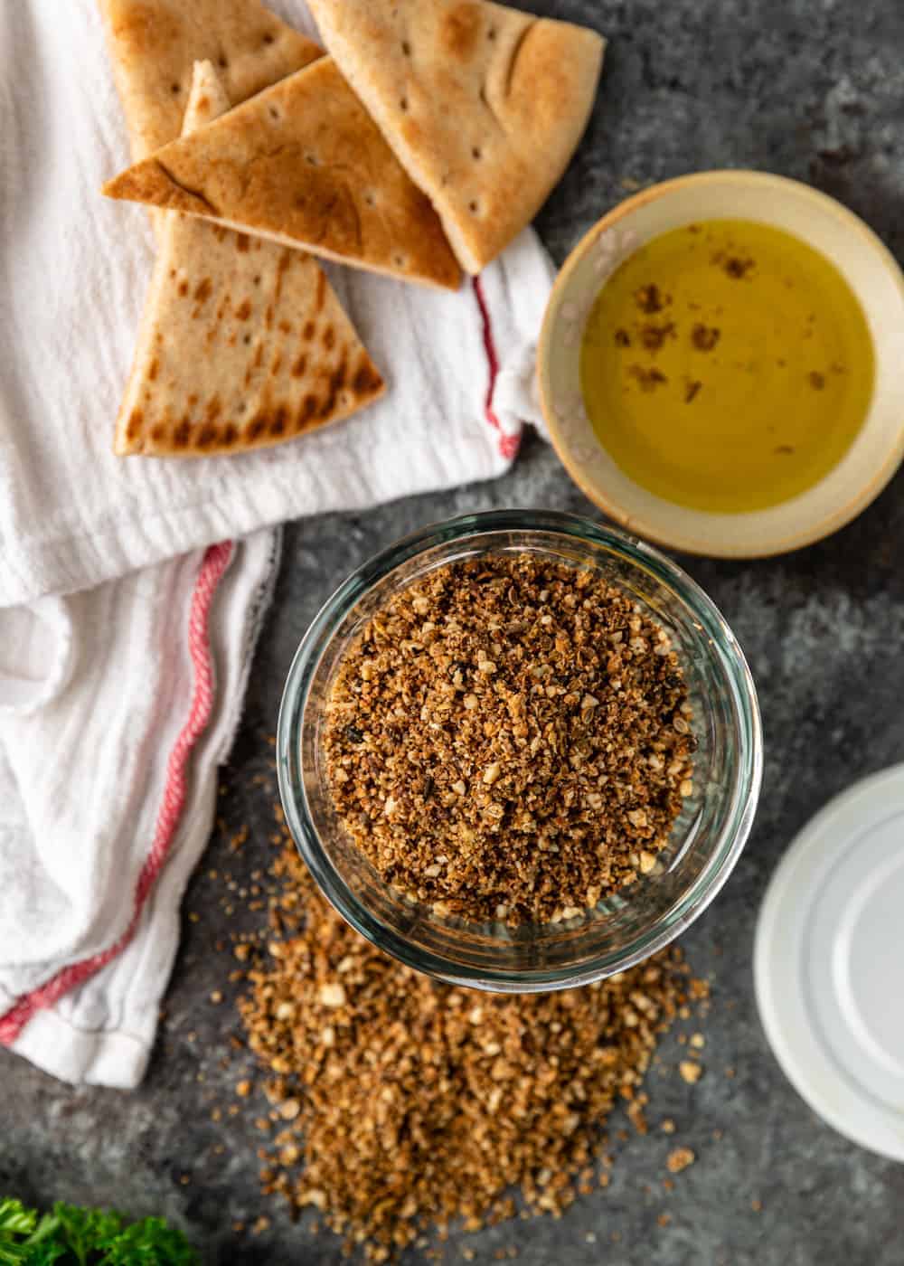 overhead image: bowl of homemade spice blend made from toasted almonds, seeds, and spices next to pita bread and dipping sauce