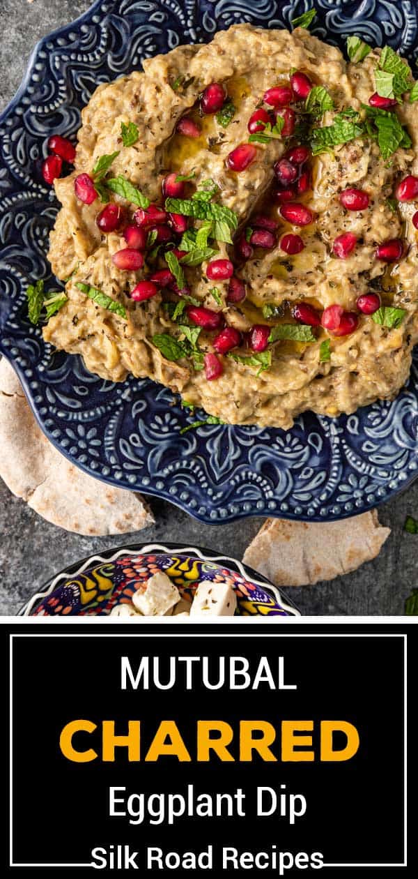 eggplant dip in blue plate with pomegranate and chopped mint