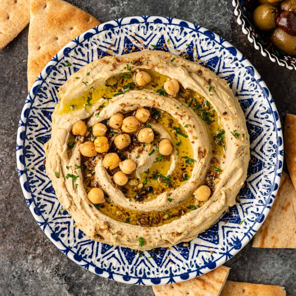 overhead image: bowl of homemade Mediterranean hummus garnished with olive oil and garbanzo beans