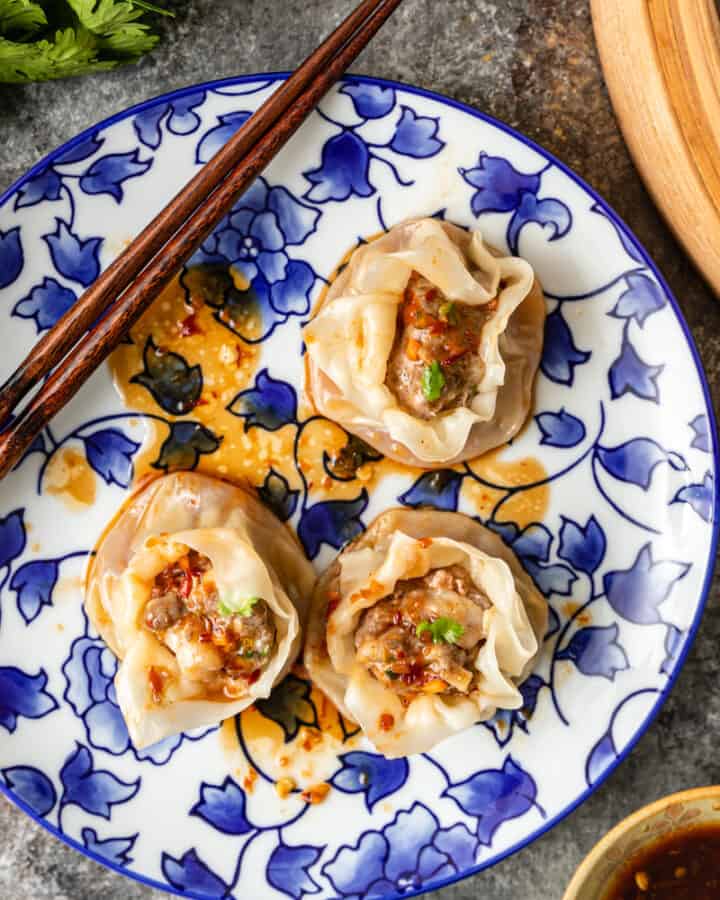 overhead photo of shrimp and pork dumplings on a blue flowered plate with chopsticks