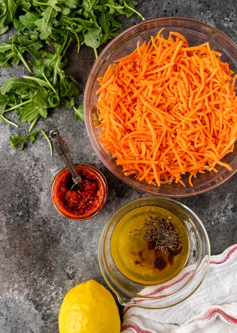 overhead: bowls of harissa carrots and vinaigrette for carrot salad recipe