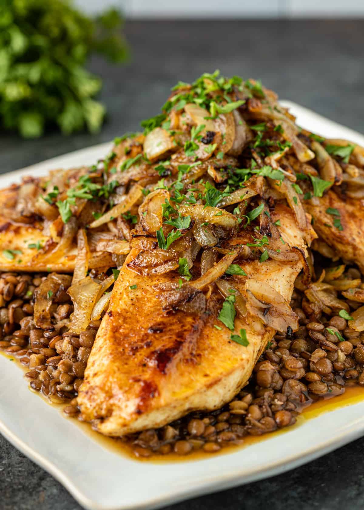 chicken and lentils with garnish of chopped parsley and sauteed onion