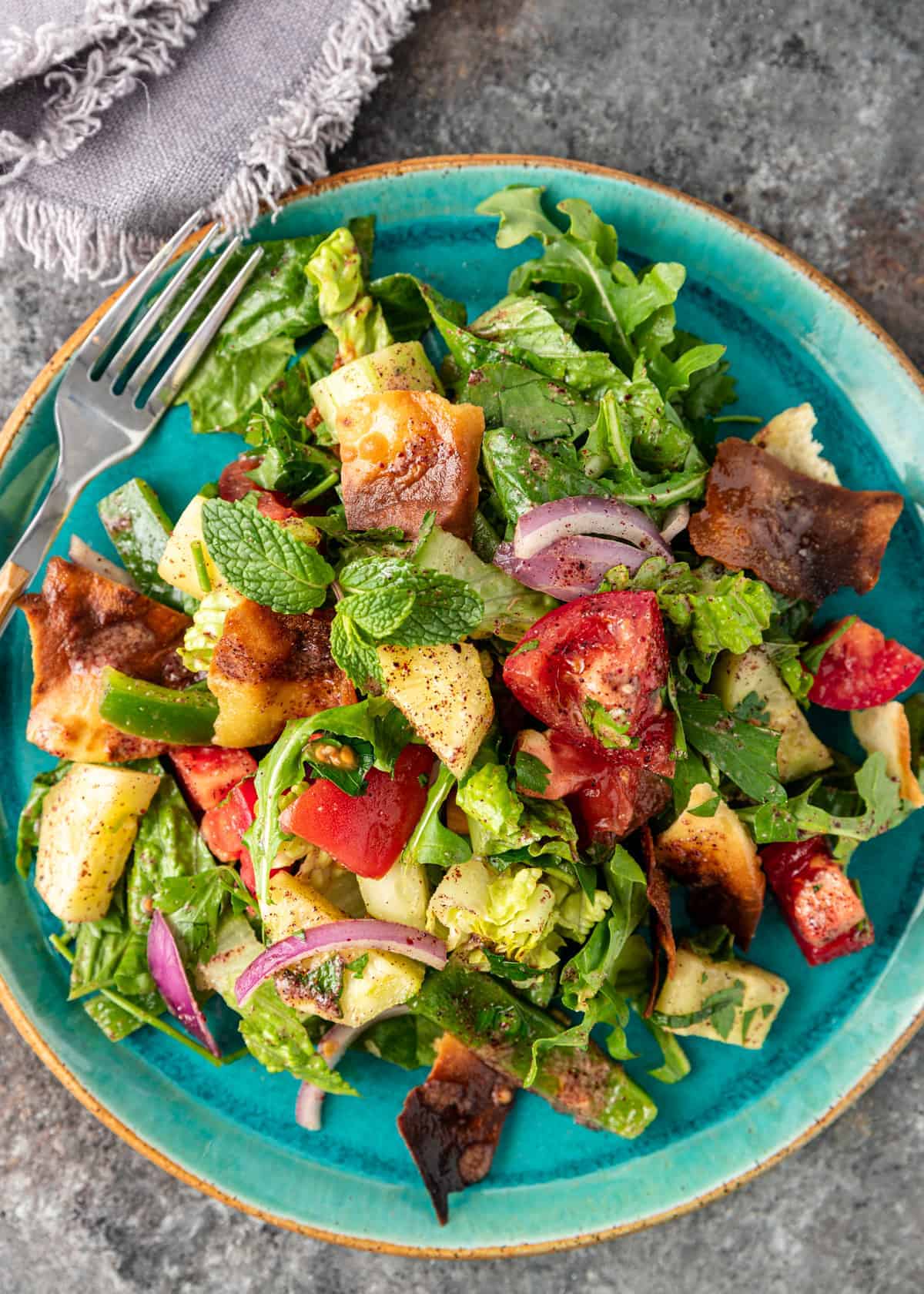 Lebanese Fattoush salad on a blue plate with a fork.