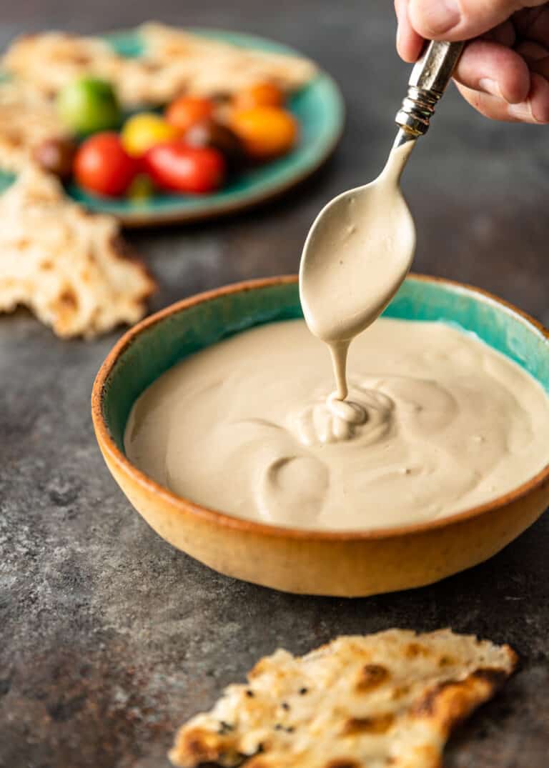 Middle Eastern tahini sauce dripping from a spoon into bowl