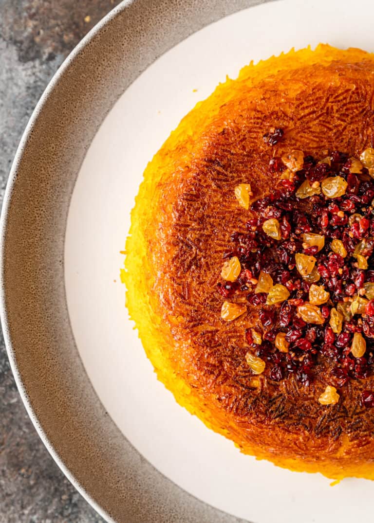 overhead image: half of a baked Persian saffron rice cake on white platter