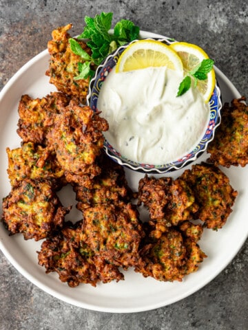 overhead: middle eastern side dish: fried vegetable patties with bowl of mint yogurt sauce for dipping