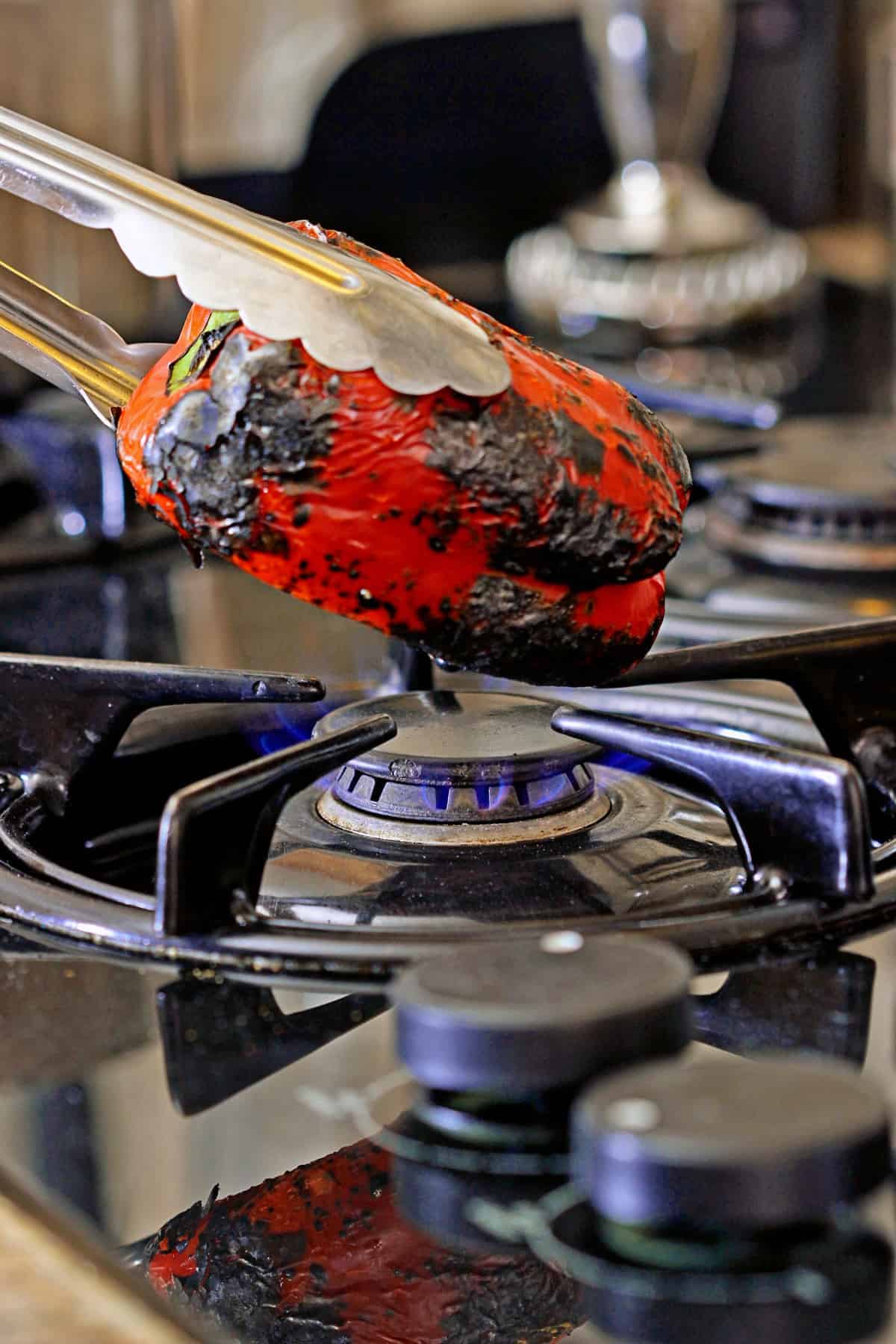 charred red bell pepper over open flame on stovetop
