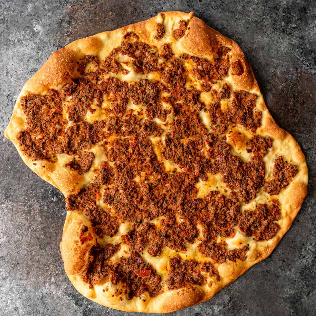 overhead image: golden brown flatbread pizza topped with lamb mince