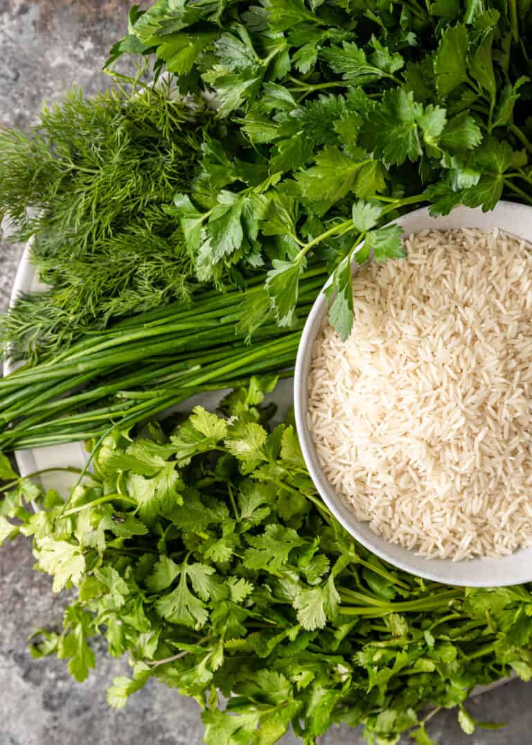 overhead: fresh herbs next to small bowl of uncooked white rice