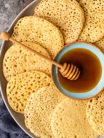 close up overhead image: platter of semolina pancakes arranged around a bowl of honey