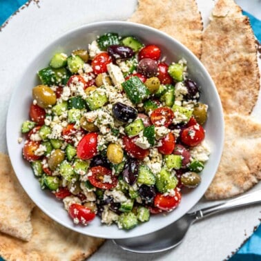 overhead image: pita bread surrounds Greek feta salad on white plate