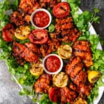overhead: large platter of harissa chicken and grilled fruit with small dishes of extra harissa for serving