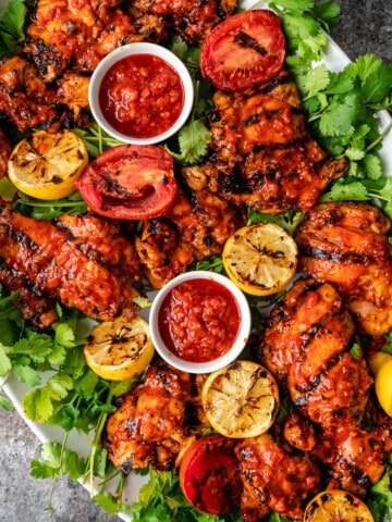 overhead: large platter of harissa chicken and grilled fruit with small dishes of extra harissa for serving