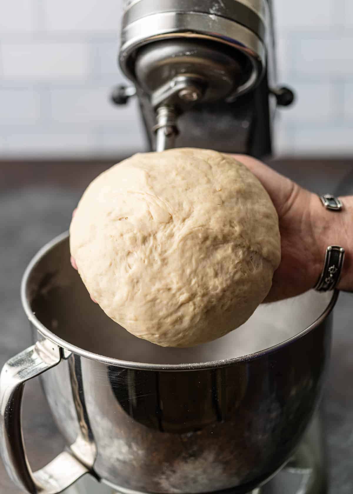 man's hand holding large ball of homemade pie dough