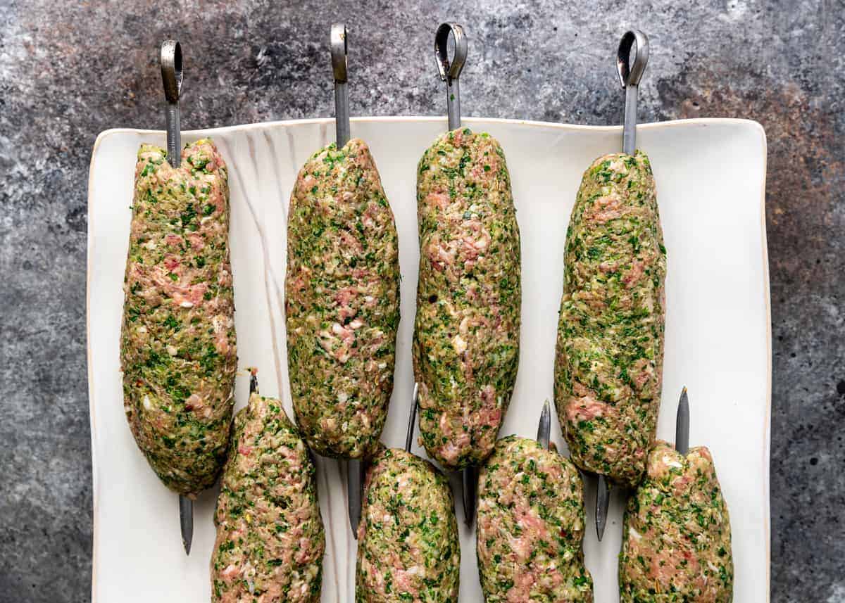 uncooked mixture of ground beef and North African spices formed around metal kabobs