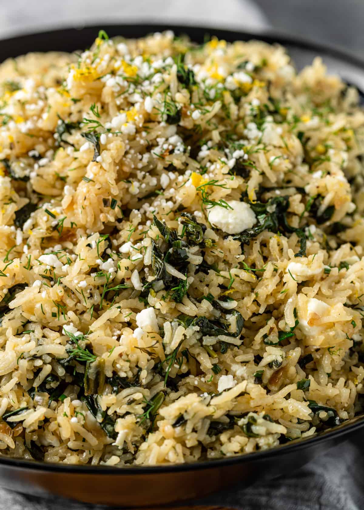 close up: bowl of long grain rice with spinach, lemon, feta cheese and Greek seasoning