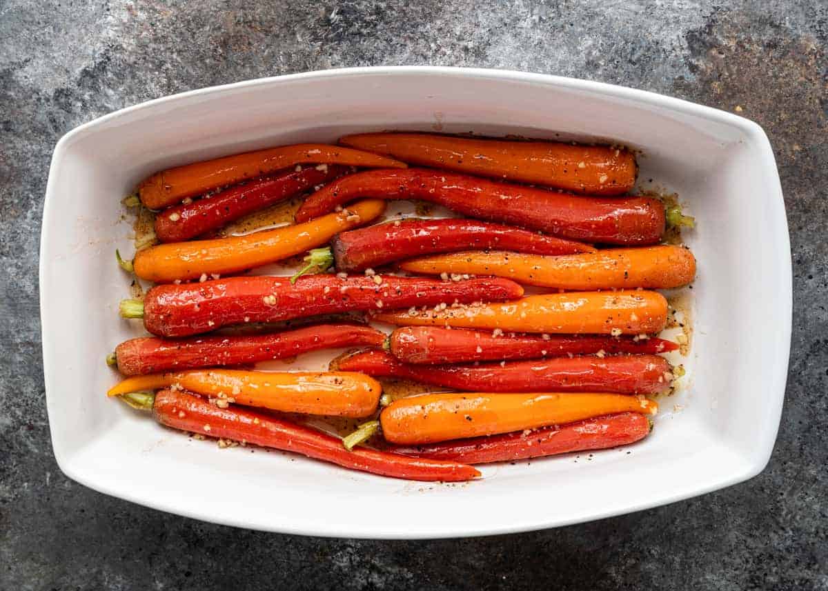 bright orange and red heirloom carrots in white rectangular baking dish