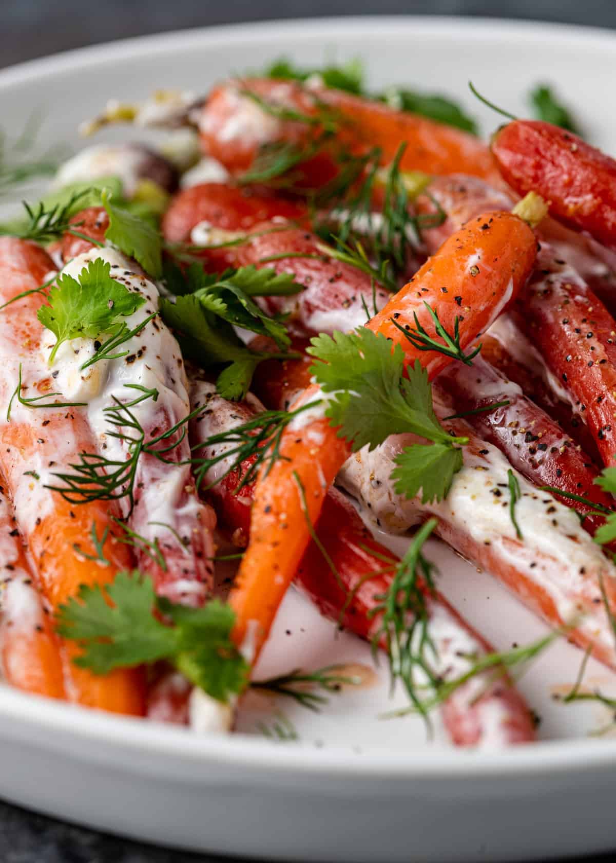 close up image of heirloom Moroccan carrots on white platter with fresh herbs