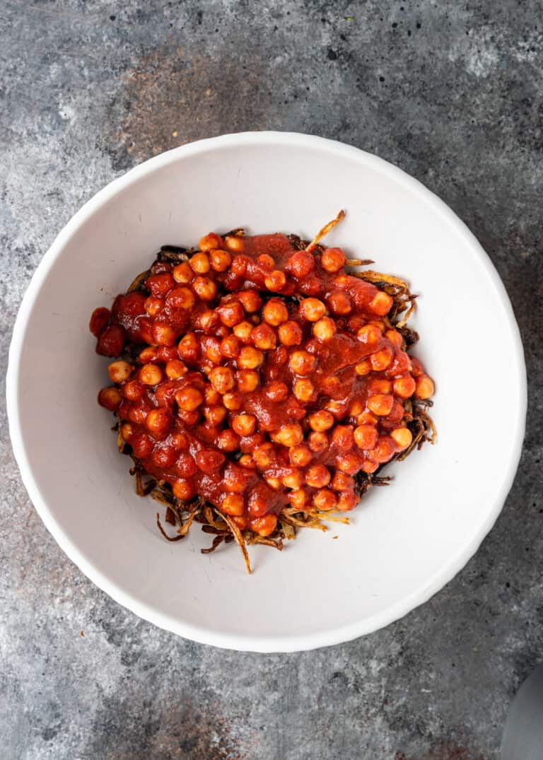 overhead: white bowl with chickpeas and fried onions tossed in spicy tomato sauce
