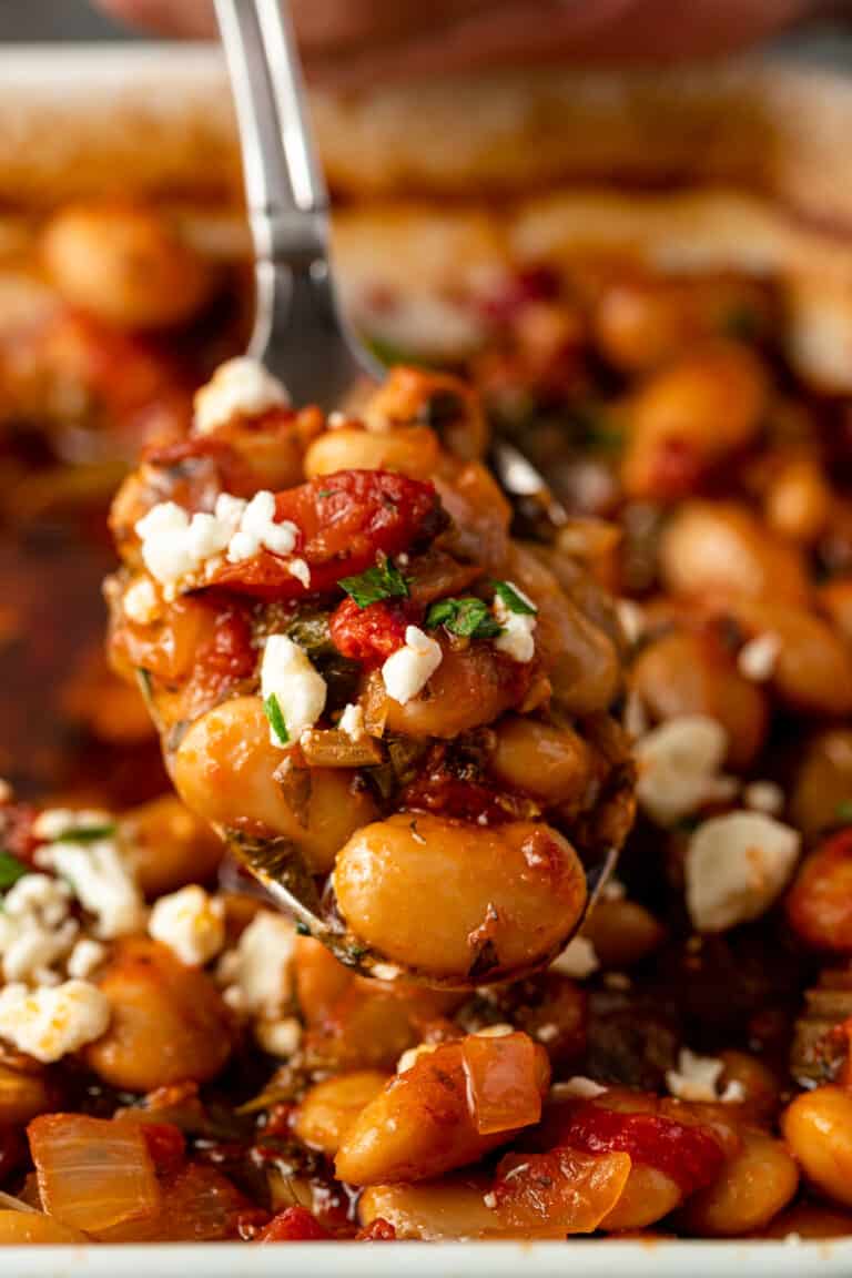 close up image: spoonful of baked Gigantes beans topped with crumbled feta cheese