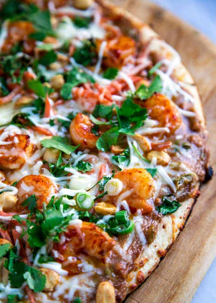 overhead image: half of a Thai pizza topped with shrimp satay