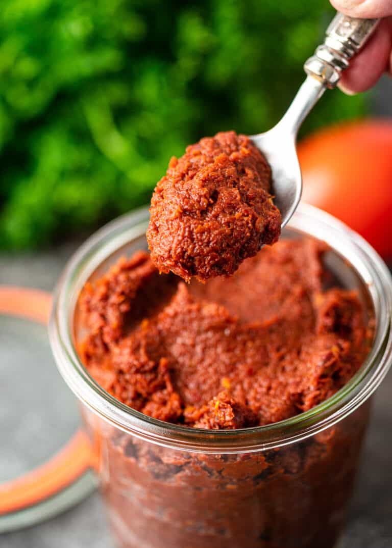 thick red pepper paste on spoon above glass jar