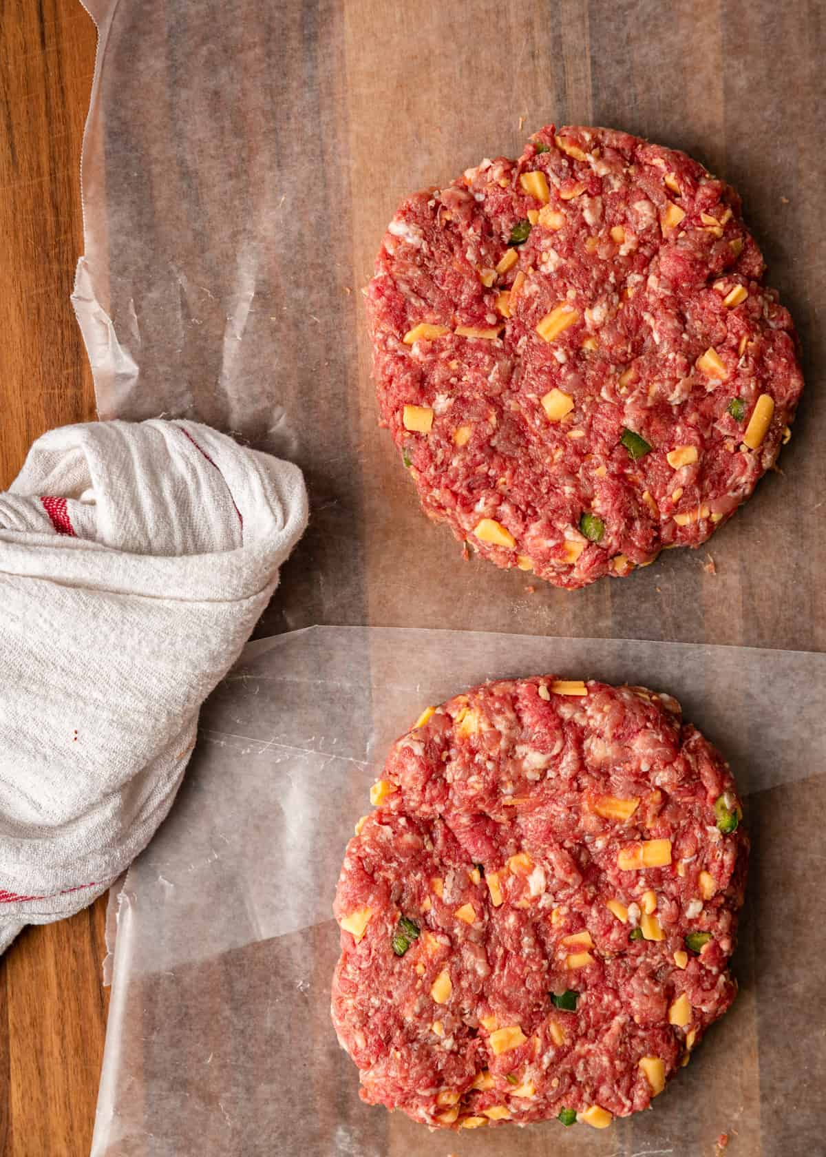 ground pork and beef burger patties (uncooked) on parchment paper