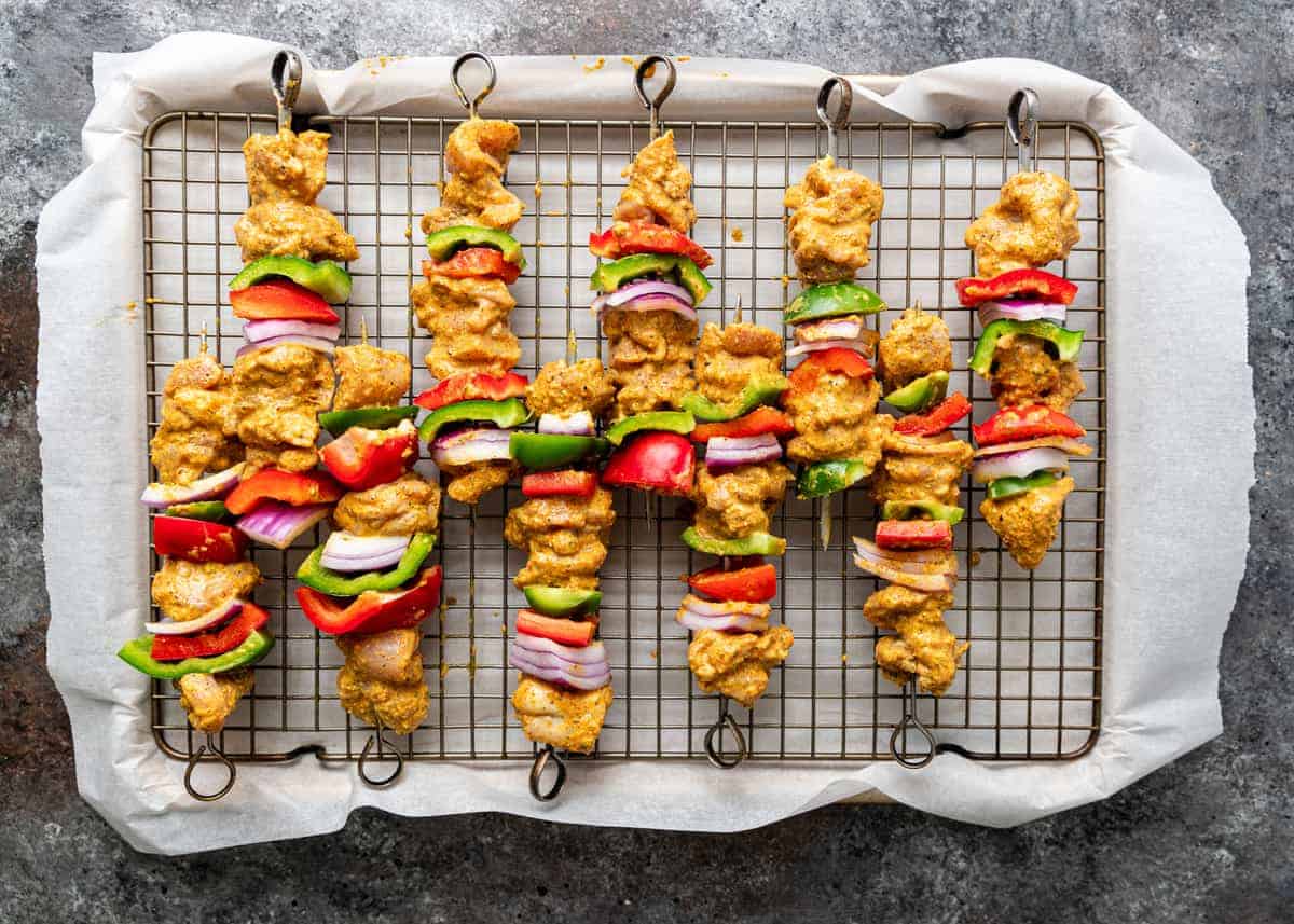 overhead: 5 skewers of tikka kabab ready for grilling
