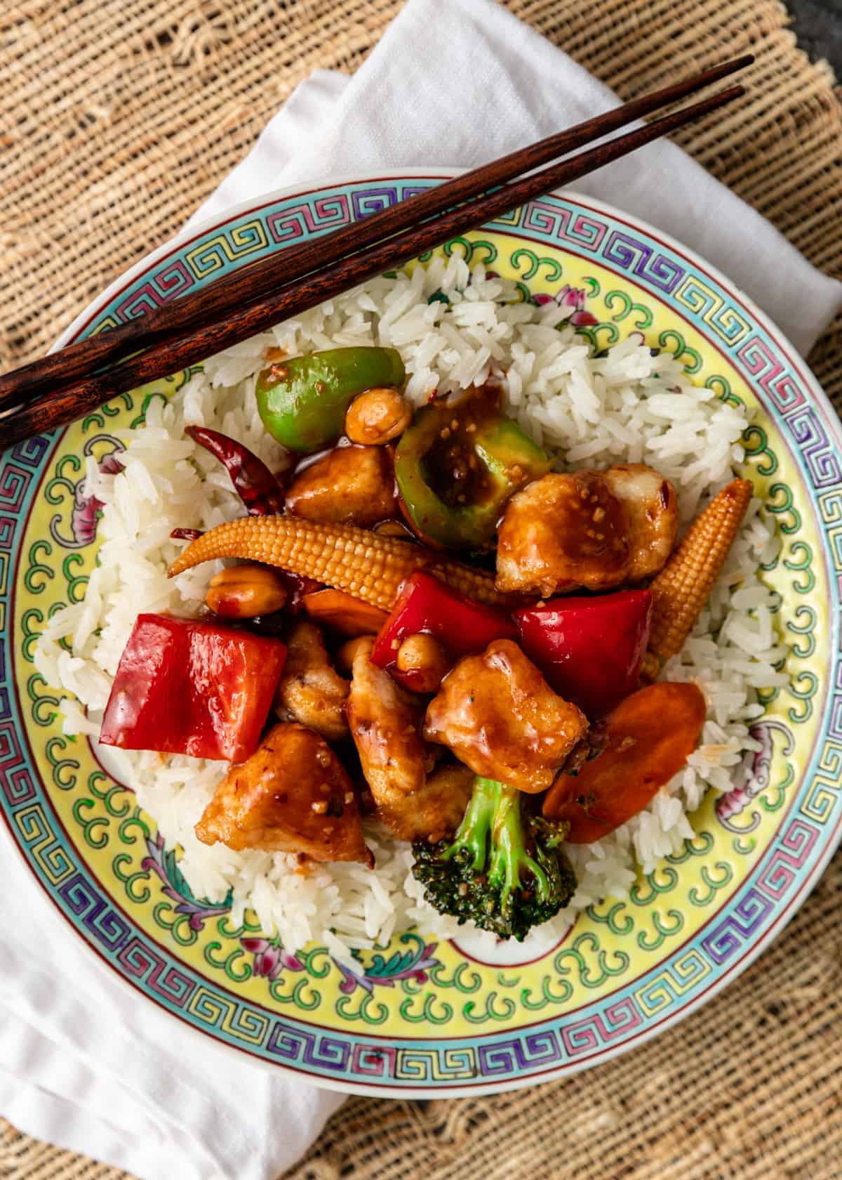 overhead: hunan chicken recipe over white rice on plate with chopsticks