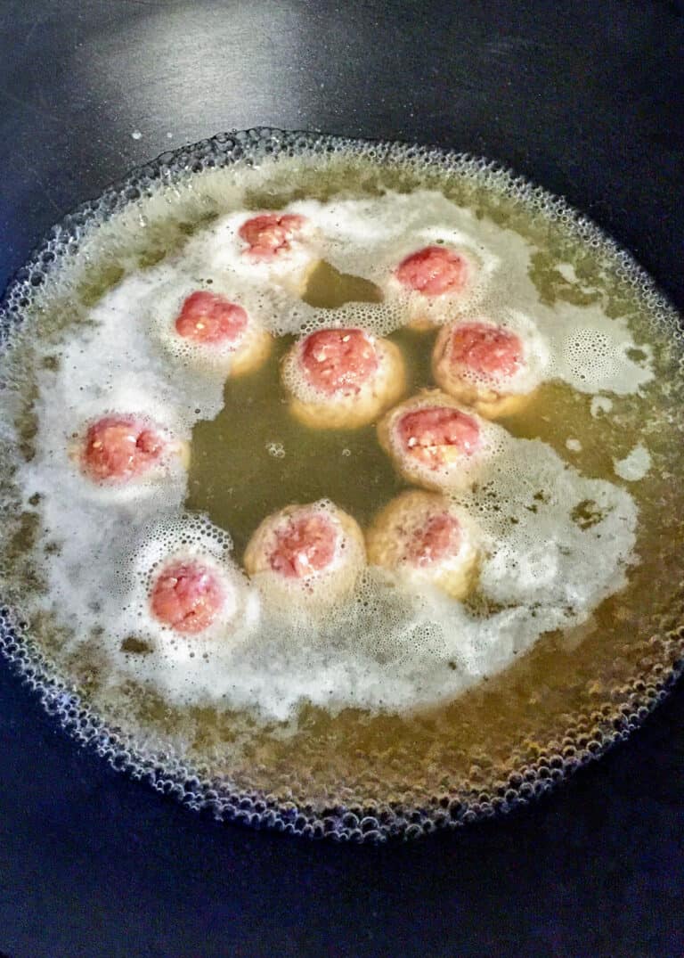 overhead: boiling meatballs in water for pork ramen recipe