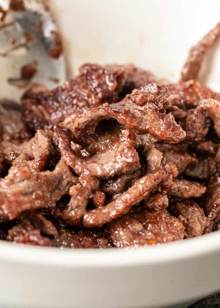 close up: stir fried strips of sirloin in white bowl