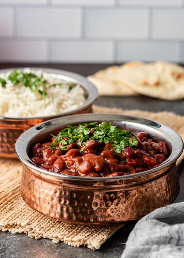 bowls of rajma masala with cilantro garnish, steamed basmati rice and naan