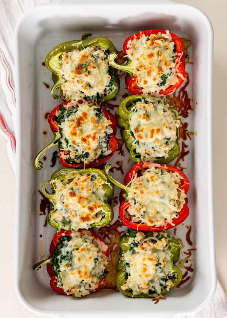overhead: red and green stuffed bell peppers in white baking dish