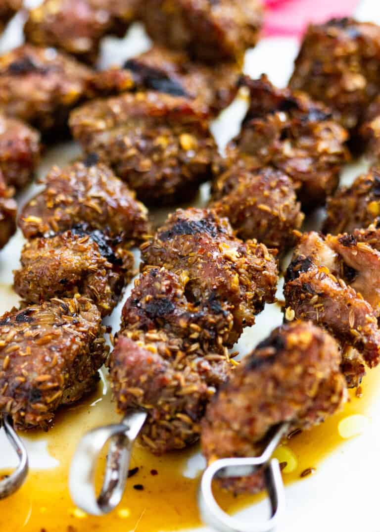 several grilled lamb skewers on a plate