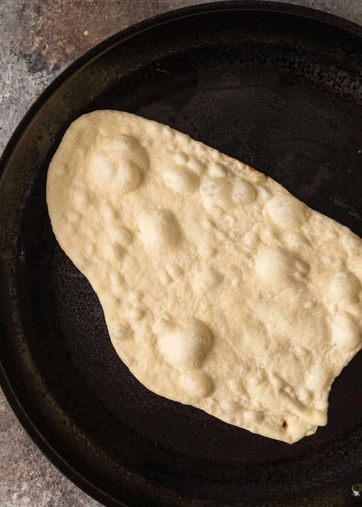 overhead: naan bread recipe with bubbles in hot skillet