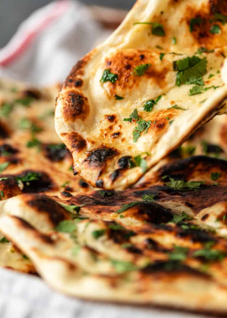 picking up garlic naan with cilantro on tray
