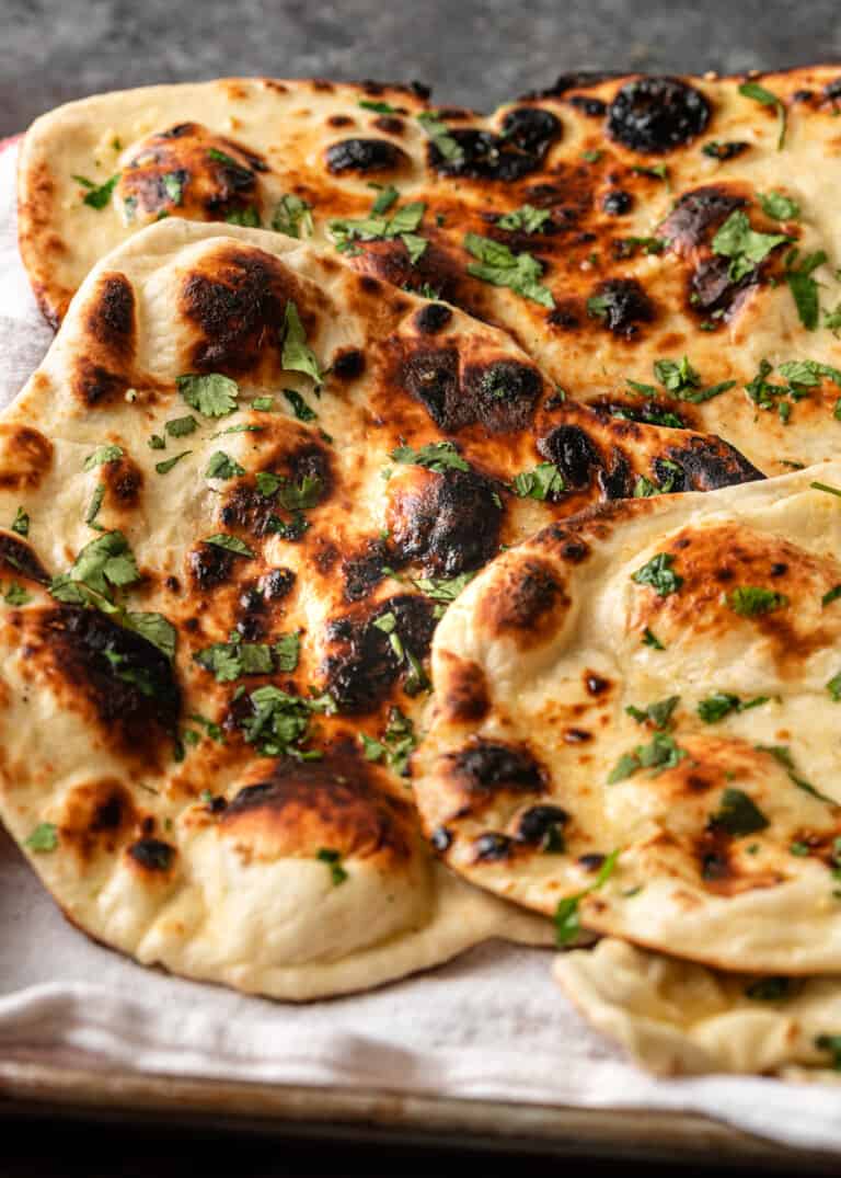 close up of buttered garlic naan with cilantro on tray