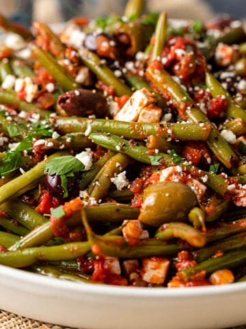 close up of Fasolakia - Greek Green Beans in a white serving bowl.