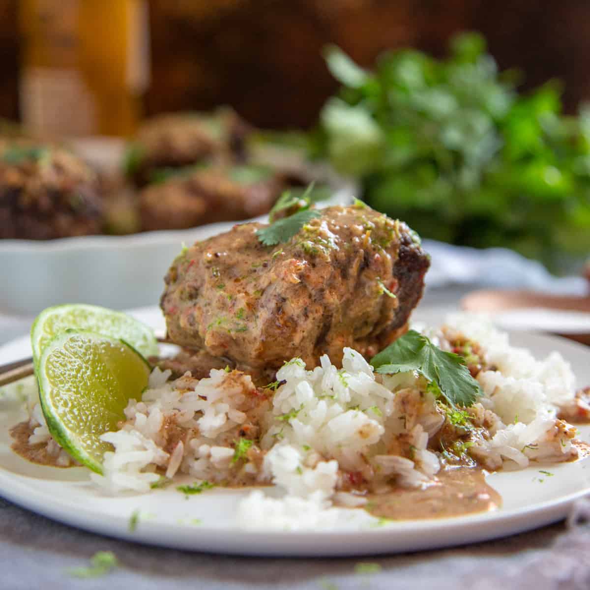 Malaysian Braised Short Ribs on a bed of rice with lime slices and fresh herbs