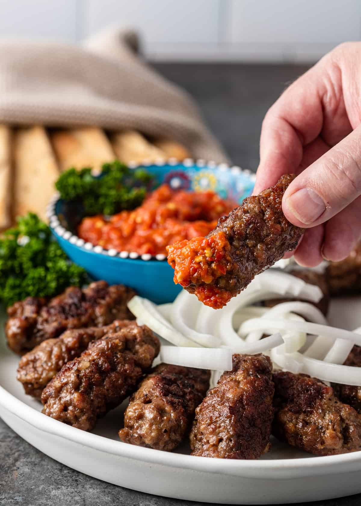 dipping Cevapi into red sauce