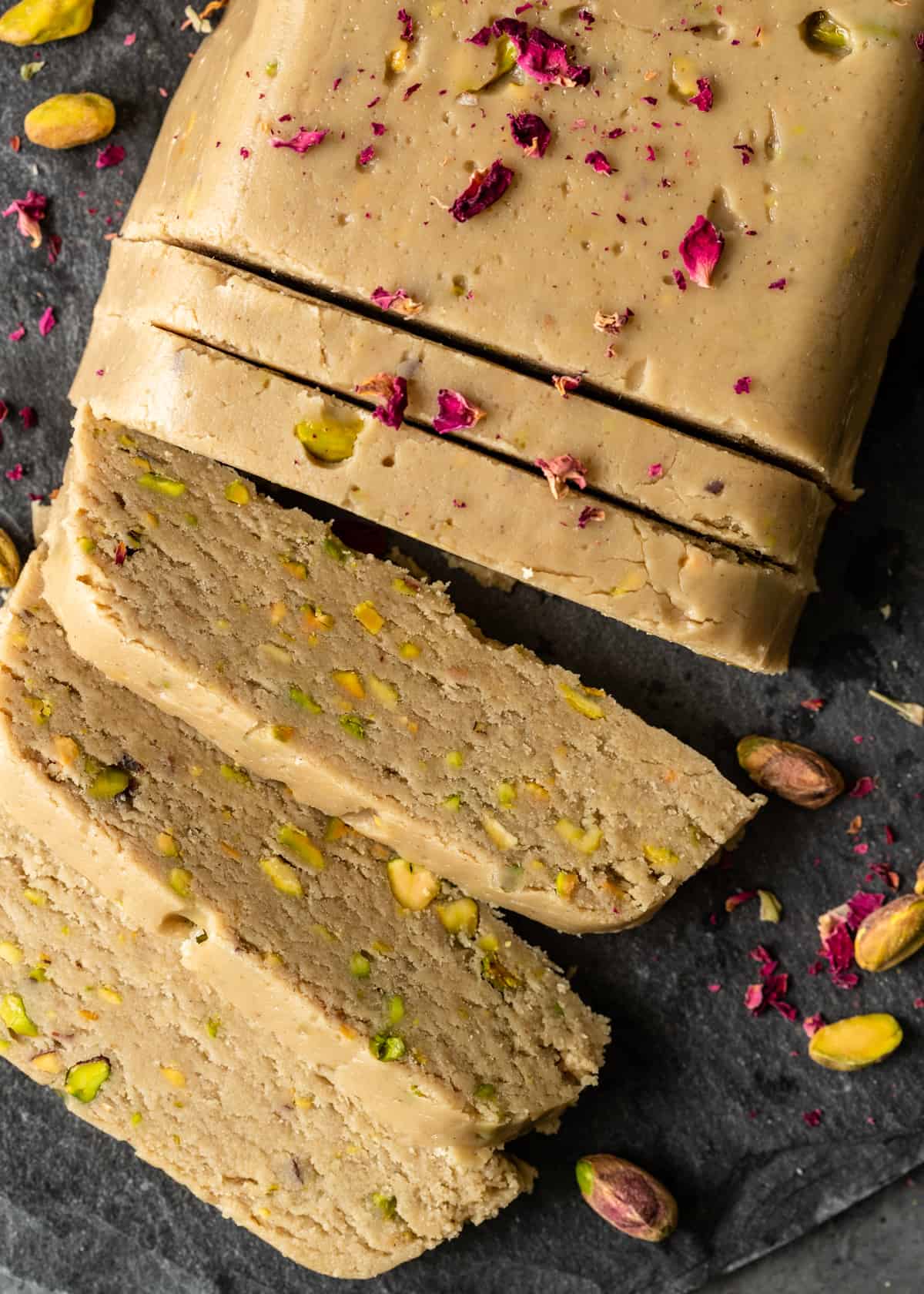overhead: slicing into a loaf of helva with pistachios showing