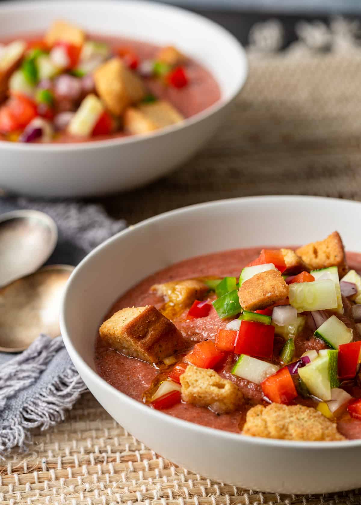 closeup: a bowl of Spanish cold soup garnished with chopped veggies and croutons