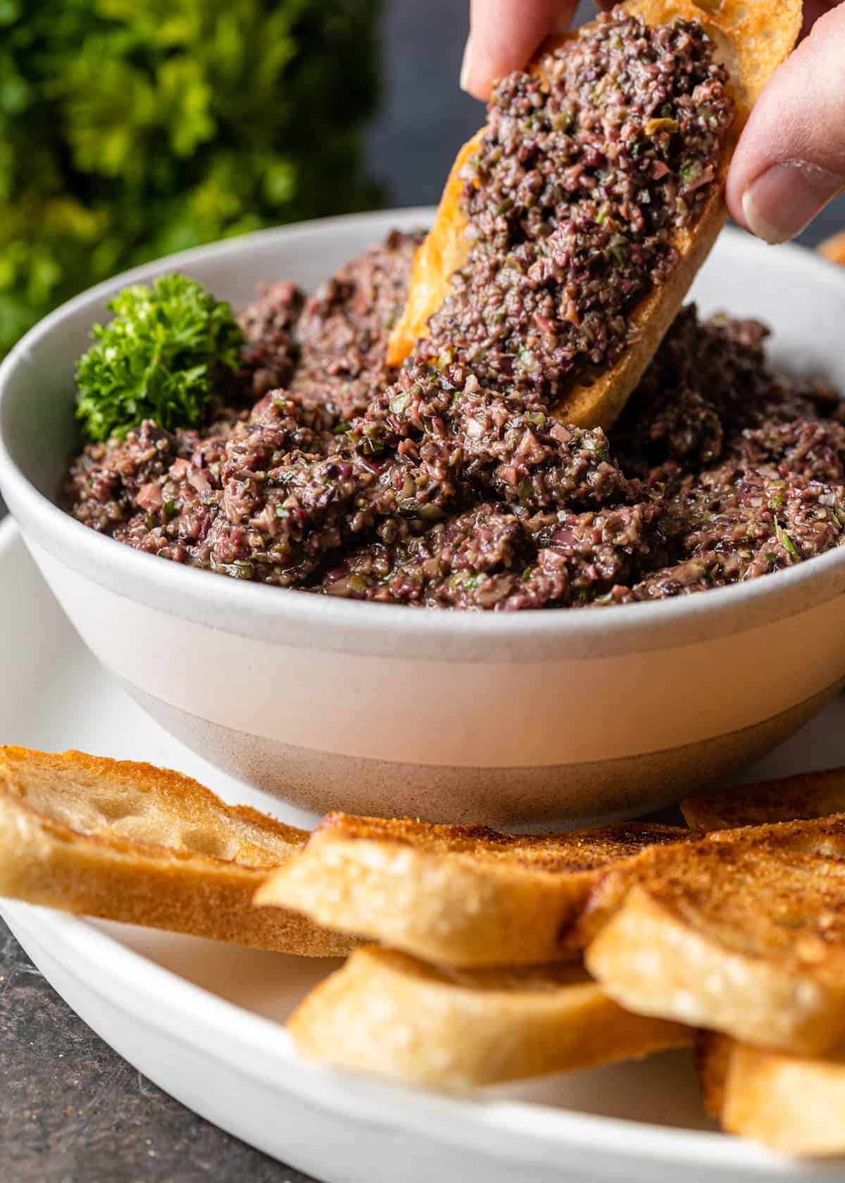 dipping bread into Olive Tapenade