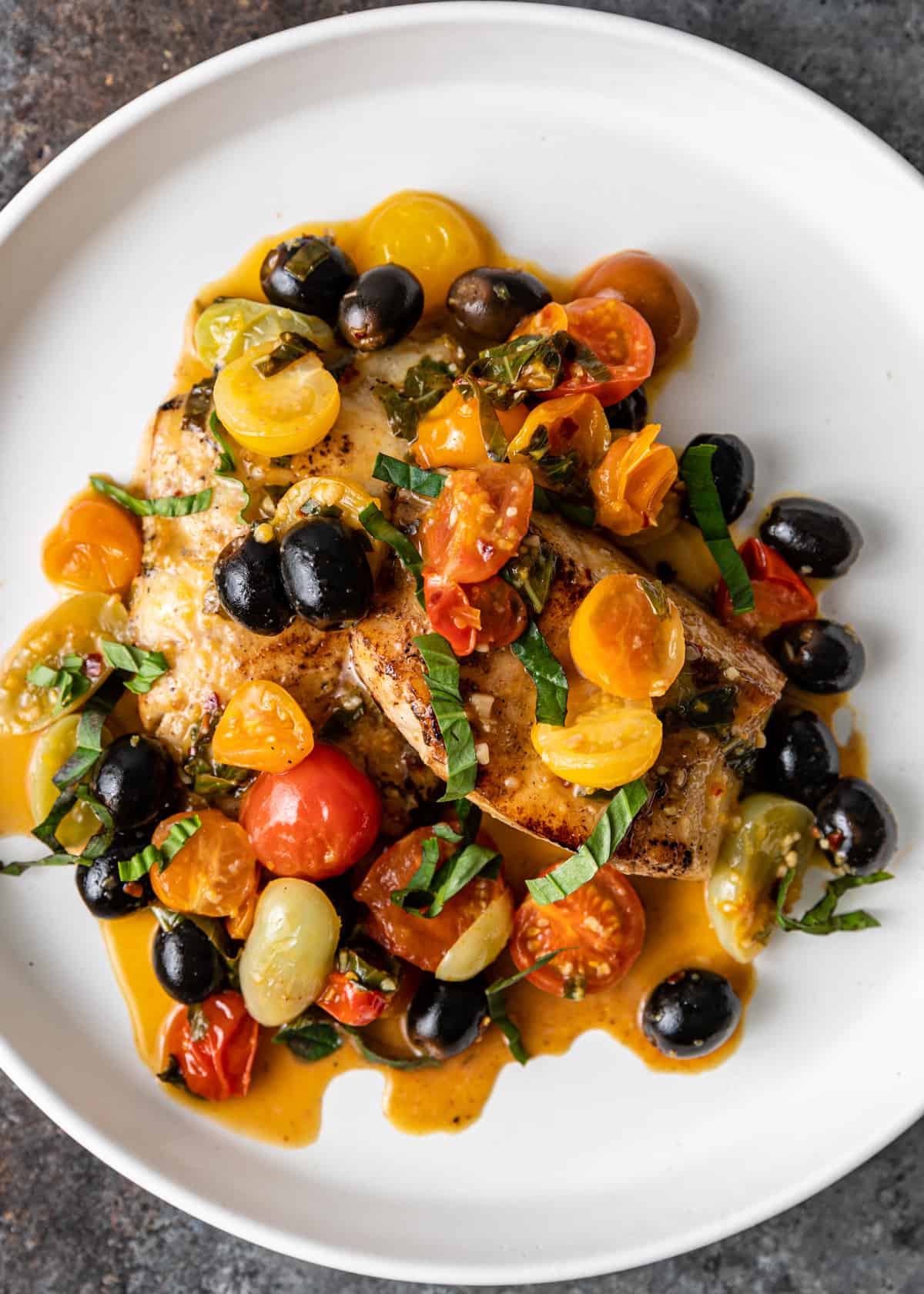 overhead: a plate full of Mediterranean pan seared cod with olives, tomatoes, and herbs