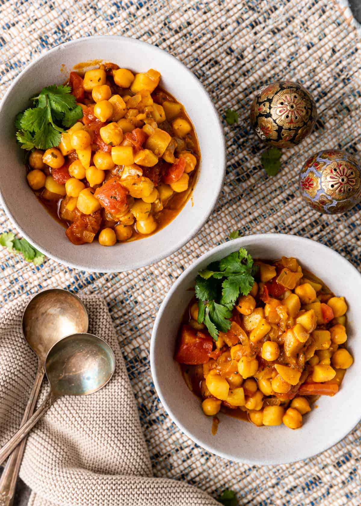 overhead view of two bowls of chickpea curry with parsley garnish