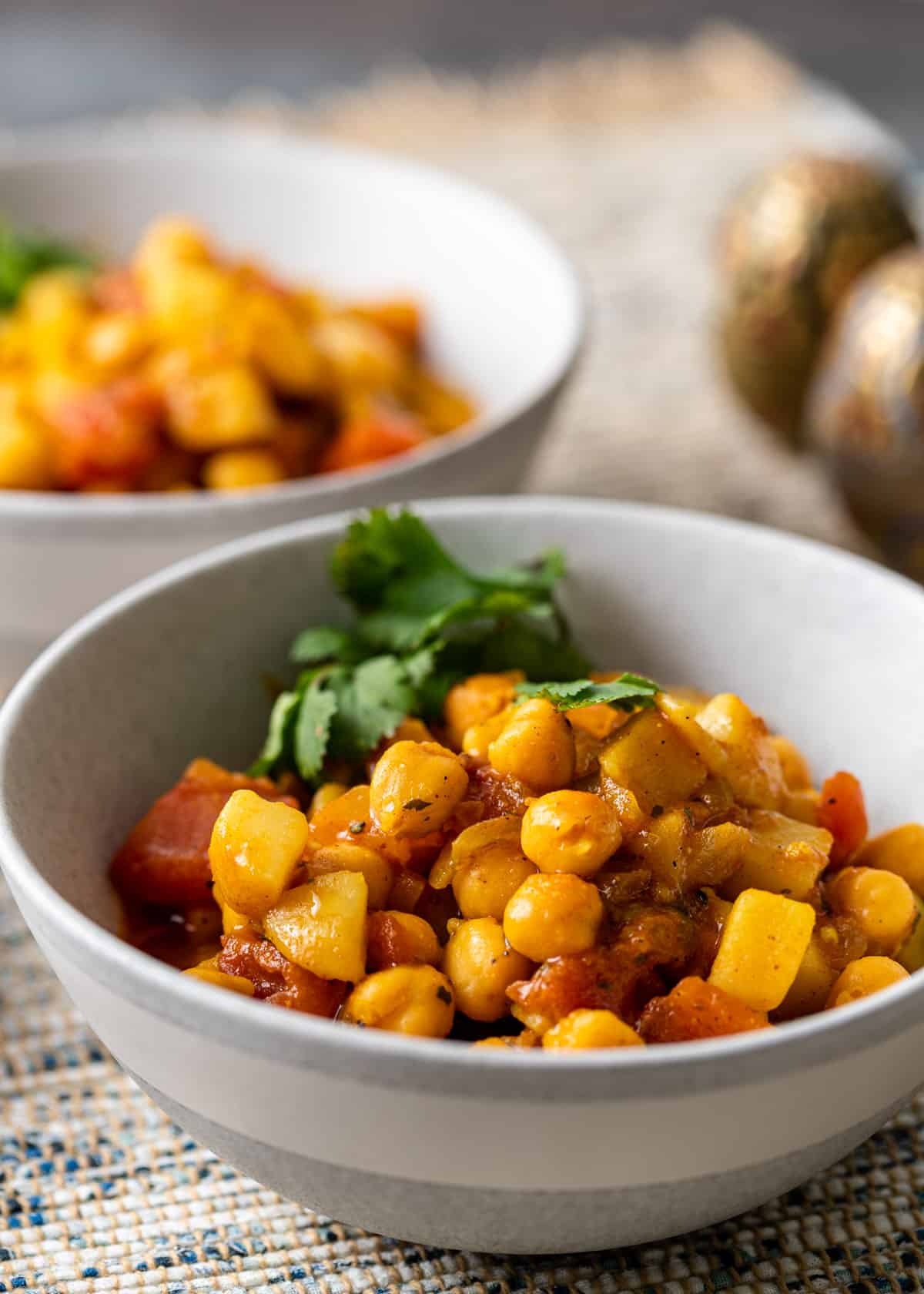 chickpea curry in a white bowl with herby garnish