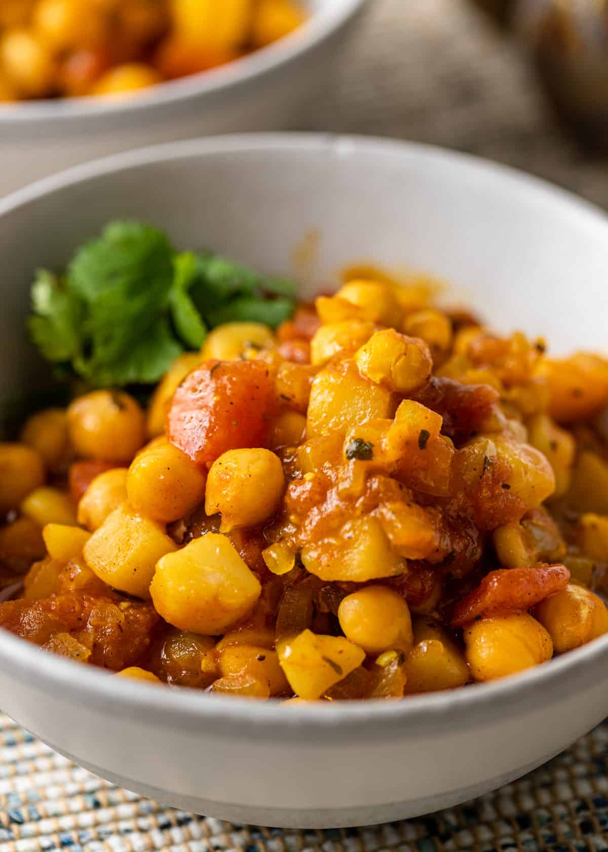 close up of chickpea potato curry in a white bowl