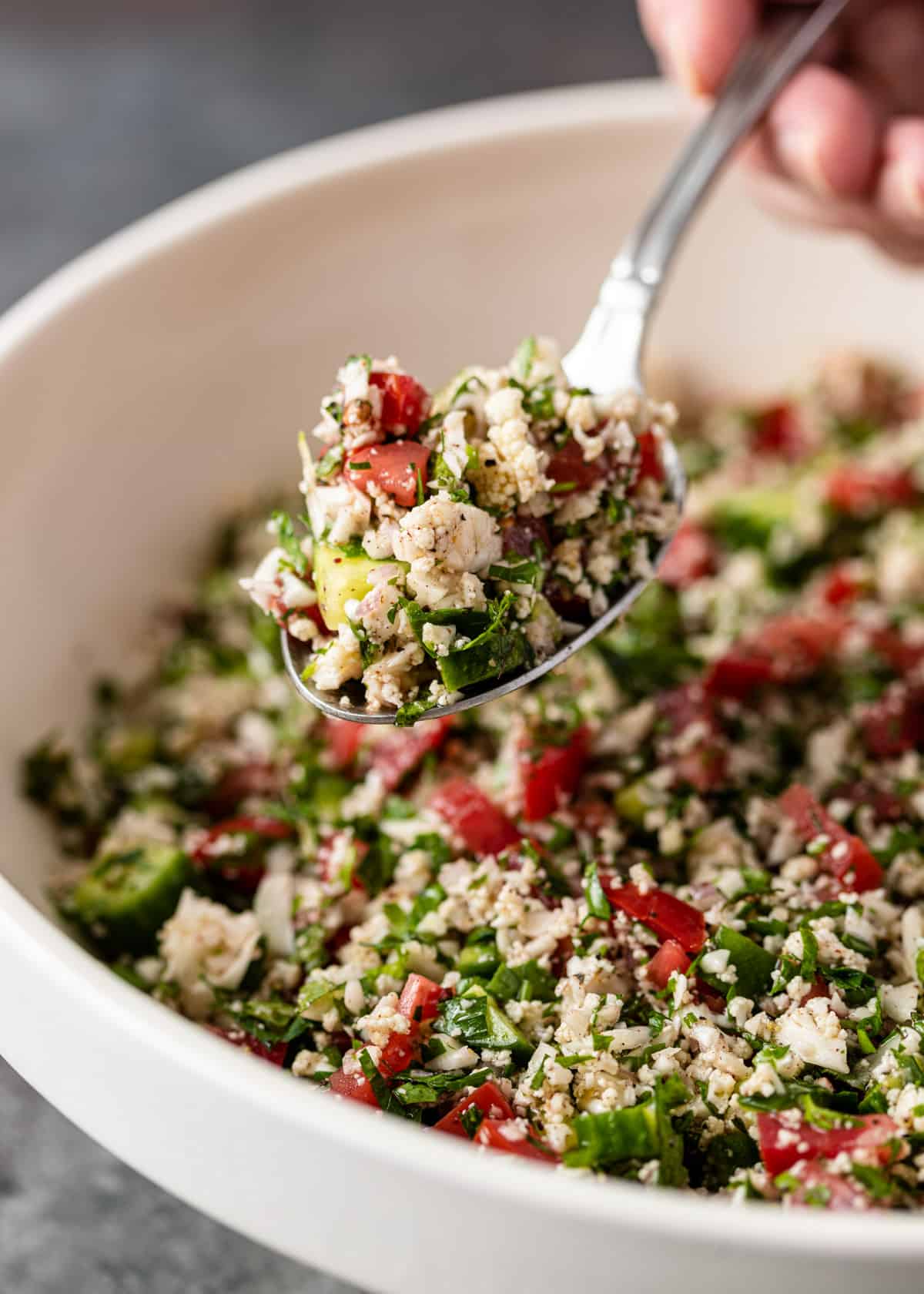 close up of cauliflower tabbouleh in a spoon over a bowl