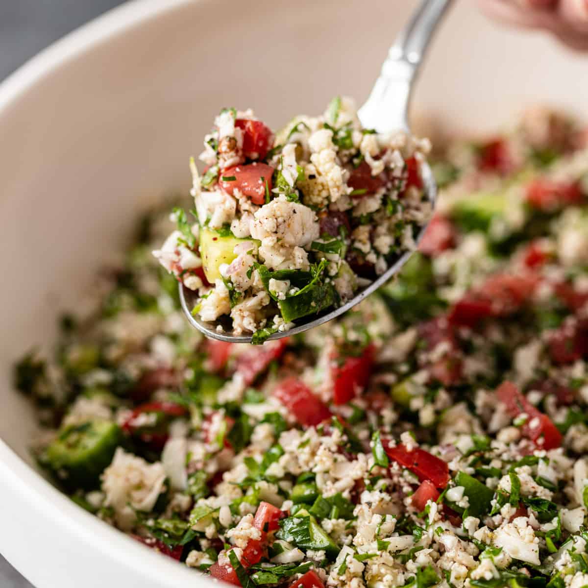 close up: cauliflower tabbouleh in a spoon over a bowl