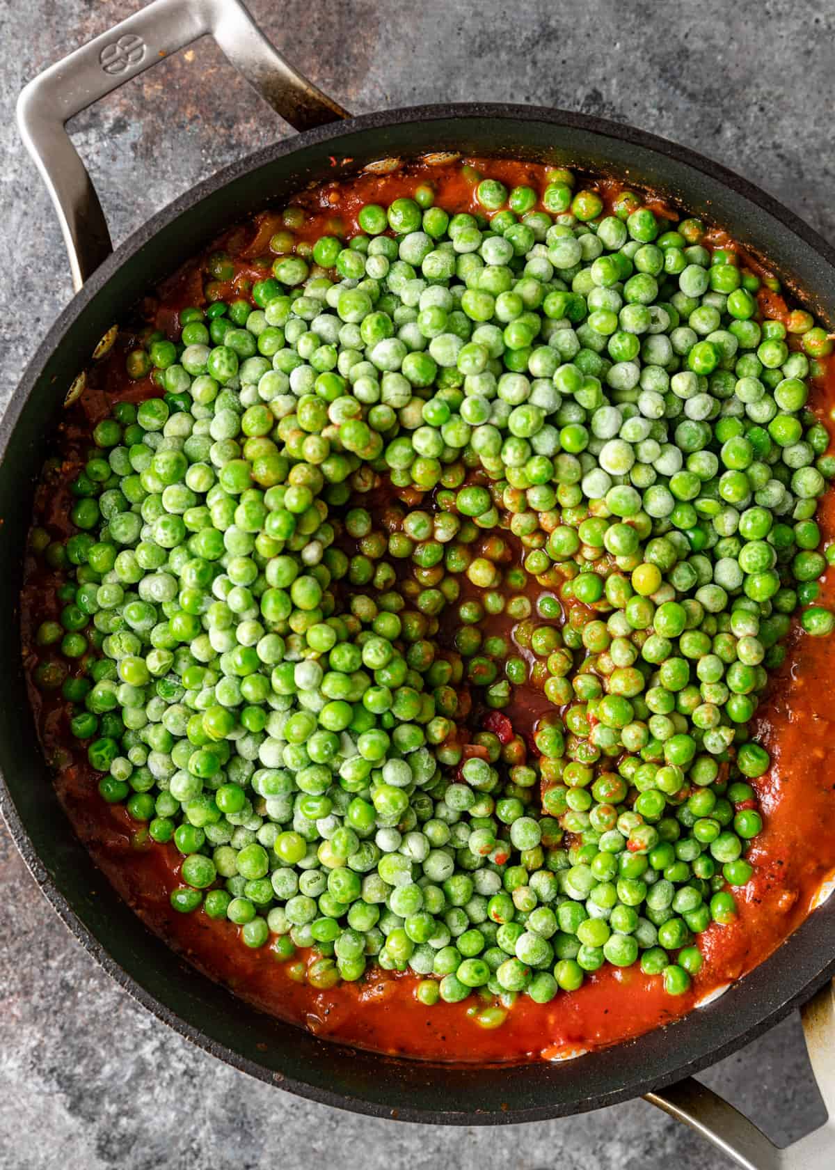 frozen peas and tomato sauce in a skillet